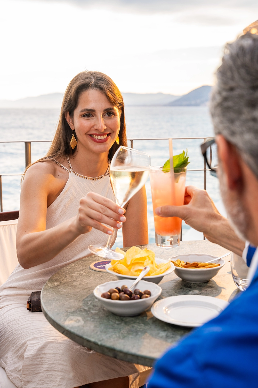 Ospite con un cocktail al bar sulla terrazza vista mare