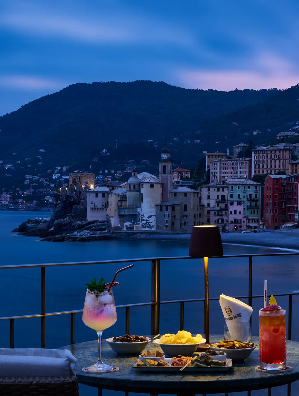 Aperitivo in terrazza al tramonto con vista su Camogli illuminata