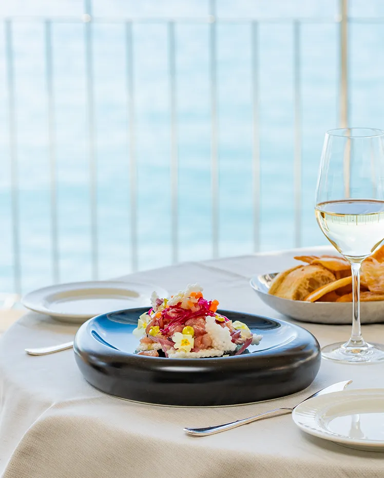 Piatto di pesce e vino bianco su una tavola apparecchiata vista mare