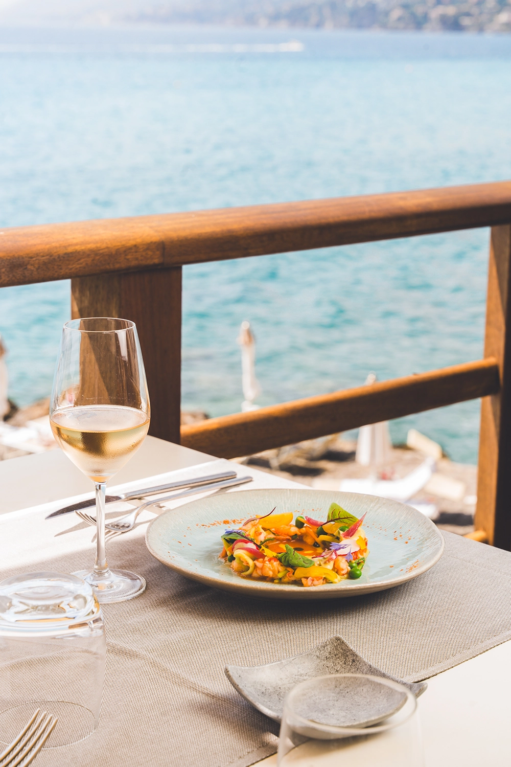 Piatto e calice di vino bianco sulla terrazza del Ristorante La Playa