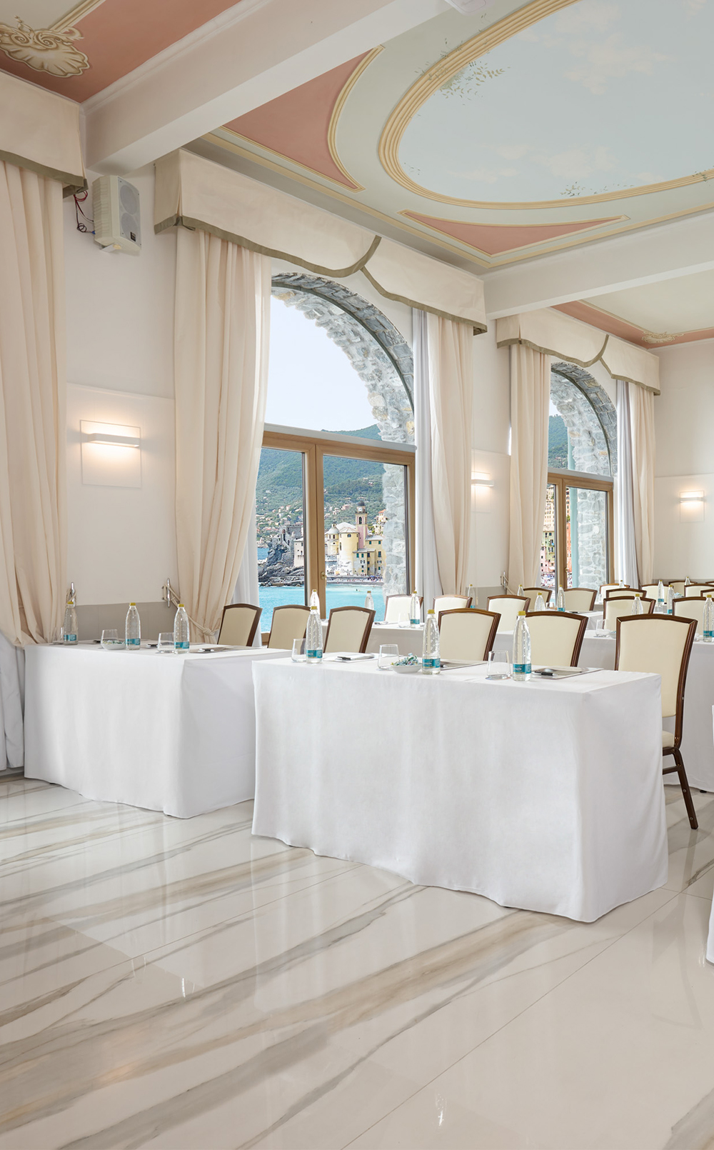 Sala Syrius con tavoli e finestre ad arco sul mare