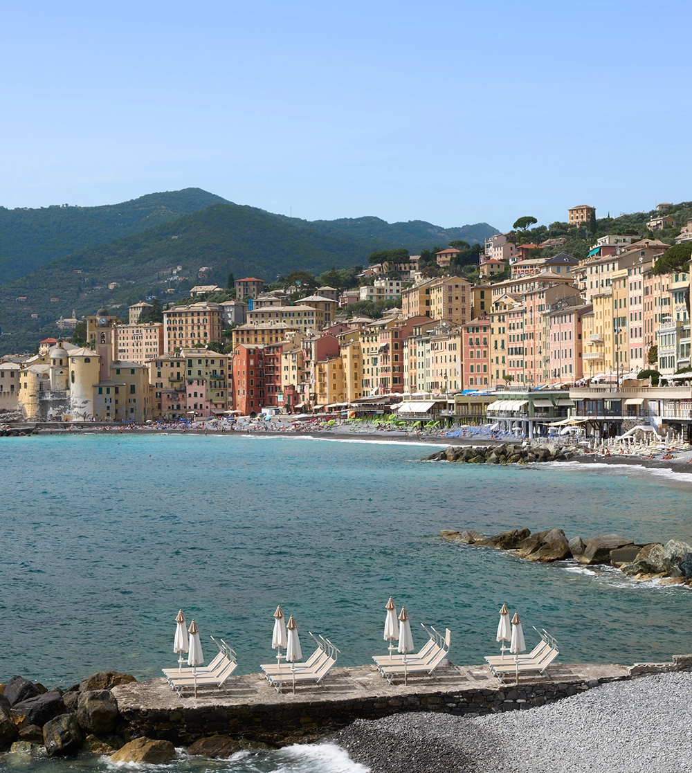 Lettini della spiaggia dell'hotel con le case colorate di Camogli sullo sfondo