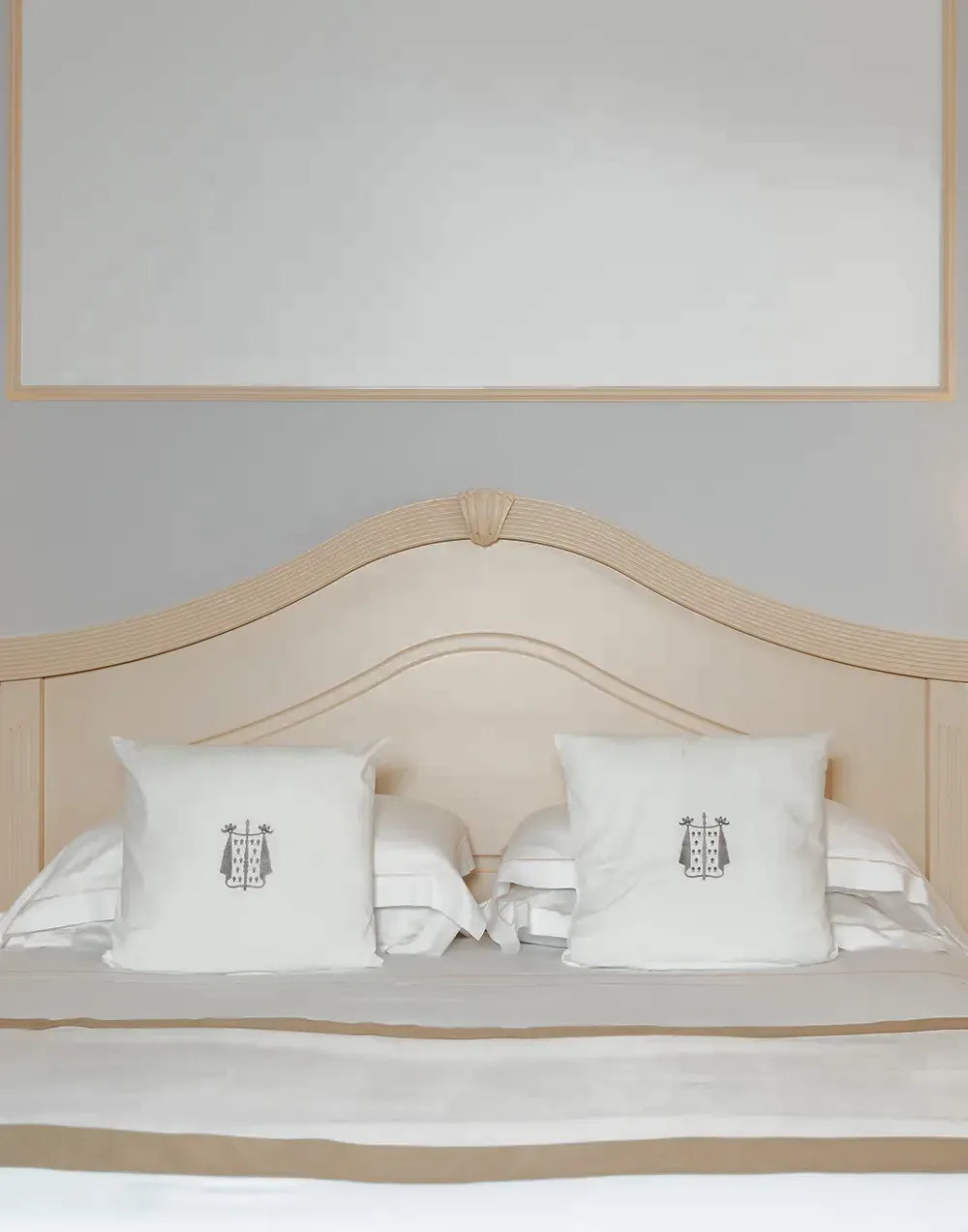 Letto della suite con cuscini ricamati con lo stemma dell'hotel